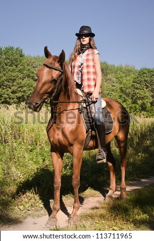 Young cowgirl riding a bay horse