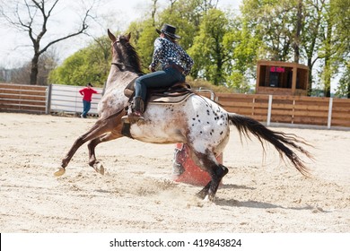 Young cowgirl riding a beautiful paint horse in a barrel racing event at a rodeo in Mitrov, Czech republic