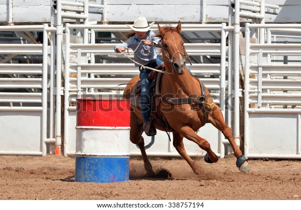 Young\
cowgirl riding a horse around a barrel in a\
rodeo.