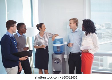 Young coworkers discussing while standing at office