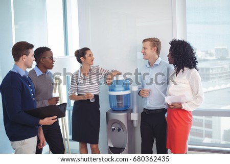 Young coworkers discussing while standing at office