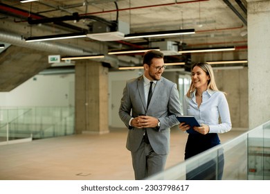 Young coworkers walking and talking along corridor in the modern office - Powered by Shutterstock