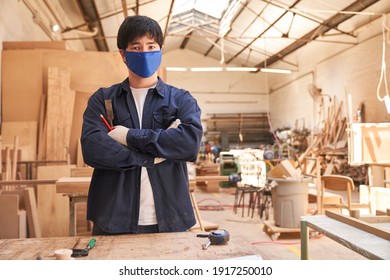 Young Craftsman Apprentice With Face Mask Because Of Covid-19 In The Joinery