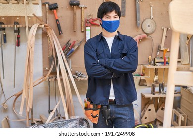 Young Craftsman As A Carpenter Apprentice With Face Mask Because Of Covid-19