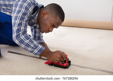 Young Craftsman Installing Carpet On Floor Using Fitter