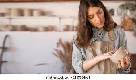 young craftswoman focused on sculpting a raw clay bowl during a pottery class at a creative studio. female ceramic business owner makes crafts for sale in a handmade pottery retail store. copy space. - Powered by Shutterstock