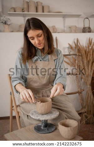 Similar – Young female sitting by table and making clay or ceramic mug