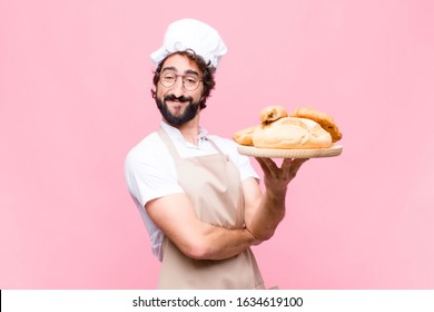 Young Crazy Baker Man Holding Bread Against Pink Wall