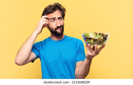 young crazy bearded athlete doubting or uncertain expression and diet concept
