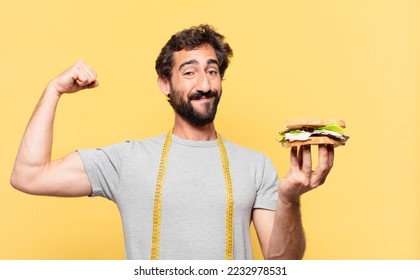 young crazy bearded man dieting happy expression and holding a sandwich - Shutterstock ID 2232978531