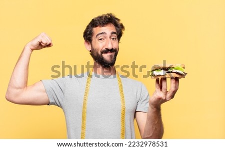 young crazy bearded man dieting happy expression and holding a sandwich