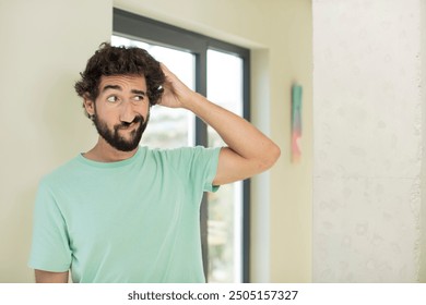 young crazy bearded man feeling puzzled and confused, scratching head and looking to the side - Powered by Shutterstock