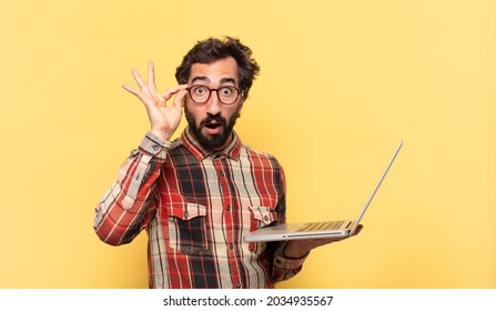 young crazy bearded man surprised expression and a laptop
