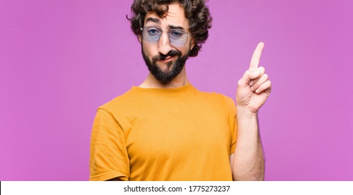 young crazy cool man feeling like a genius holding finger proudly up in the air after realizing a great idea, saying eureka against flat wall - Shutterstock ID 1775273237