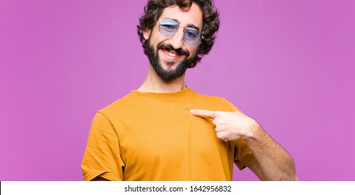 young crazy cool man looking happy, proud and surprised, cheerfully pointing to self, feeling confident and lofty against flat wall - Shutterstock ID 1642956832