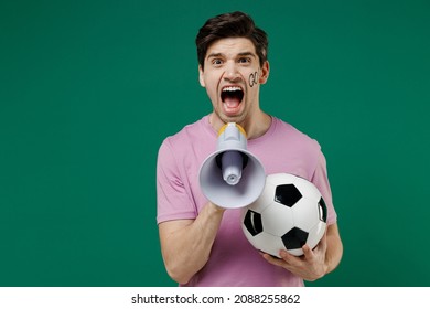 Young Crazy Fun Man Fan Wears Basic Pink T-shirt Cheer Up Support Football Sport Team Hold In Hand Soccer Ball Watch Tv Live Stream Scream In Megaphone Isolated On Dark Green Color Background Studio