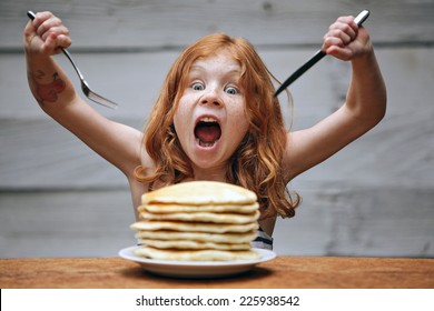 Young crazy girl eating a stack of pancakes. 