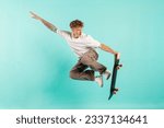 young crazy guy rides skateboard and jumps on blue isolated background, hipster in sunglasses flies with skateboard in the air and does extreme trick