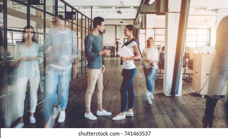 Young creative people in modern office. Successful hipster team in coworking. Businesspeople walking in the corridor of an business center. Motion blur. Couple of freelancers are discussing new ideas. - Powered by Shutterstock