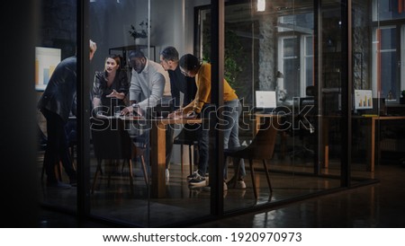 Young Creative Team Meeting with Business Partners in Conference Room Behind Glass Walls in Agency. Colleagues Sit Behind Conference Table and Discuss Business Opportunities, Growth and Development.