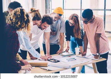 Young crew of male and female designers in casual trendy outfit communicating during conference using technology for improving planning.Skilled architects making research together drafting in studio - Powered by Shutterstock