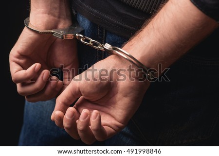Young criminal standing in handcuffs