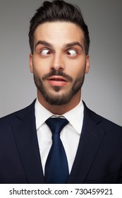 young cross eyed business man smiling on grey background