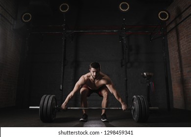 Young Crossfit Athlete Lifting Barbell At The Gym. Handsome Man Doing Functional Training. Practicing Powerlifting. Deadlift Exercise. 