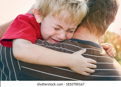 Young crying boy being comforted by his father