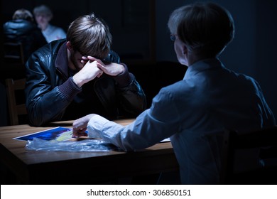 Young crying criminal in police interrogation room