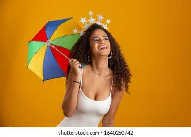 Young curly hair woman celebrating the Brazilian carnival party with Frevo umbrella on yellow.