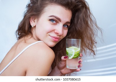 
Young Curly Woman Drinks Water With Cucumber And Lemon
