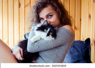 Young Curly Woman In Grey Cloth Hugs The Cat