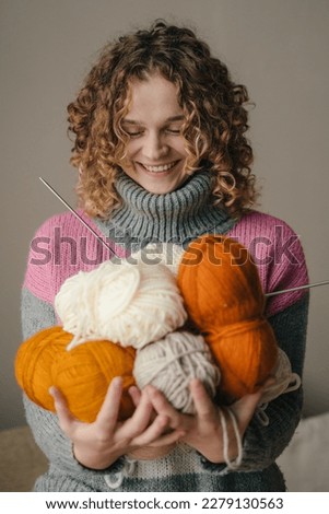 Young curly-haired woman holding many colorful yarn clews. Concept of freelance creative working and living. Domestic lifestyle. Fashion portrait. Freelance