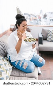 Young Curvy Mexican Woman Eating Salad Sitting On The Terrace In Latin America