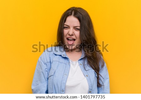 Young curvy plus size woman funny and friendly sticking out him tongue.