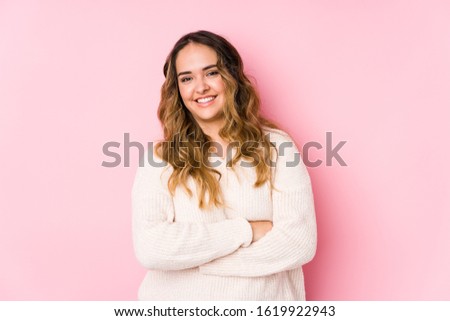 Young curvy woman posing in a pink background isolated laughing and having fun.