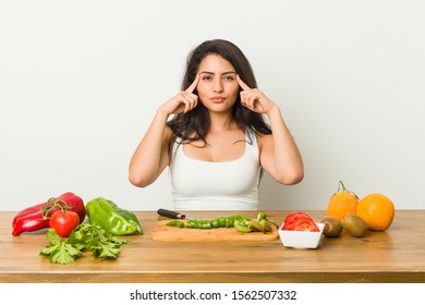 Young curvy woman preparing a healthy meal focused on a task, keeping forefingers pointing head. - Shutterstock ID 1562507332