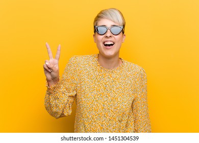 Young curvy woman wearing a floral summer clothes showing victory sign and smiling broadly. - Shutterstock ID 1451304539