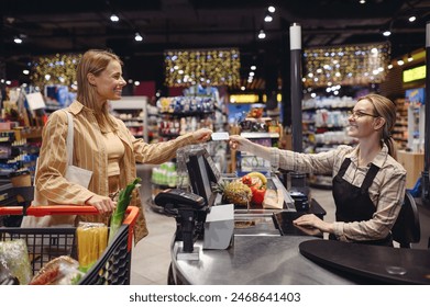 Young customer woman wear casual clothes give checkout seller cashier credit bank card shopping at supermaket store grocery shop buy with trolley cart product in hypermarket Purchasing food concept - Powered by Shutterstock