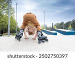 young cute boy stands on roller skates with his head down. learning to roller skate in park on summer day. Children and sports, hobbies. Active lifestyle. recreation . active cheerful childhood