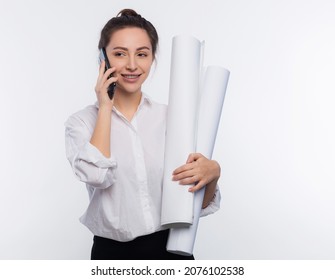 Young and cute business woman holds blueprints in her hand and use her phone. She is happy and shares the news on the phone her project was approved and she got the job isolated on white copy space
