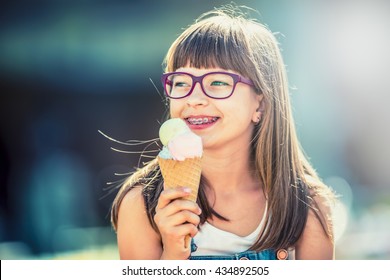 Young Cute Caucasian Blond Girl With Dental Braces Glasses And Ice Cream.