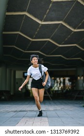 A Young And Cute Chinese Asian Girl In A Tee And Shorts Is Late And Running For Class Or The Bus. She Is Wearing A Backpack Over A Shoulder. 