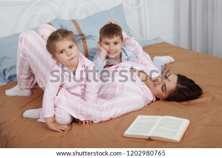 Similar – Mother reading book to her sons in the bed