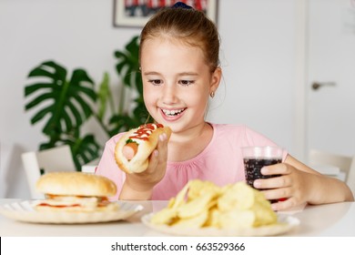 Young Cute European Girl In T-shirt Is Eating Unhealthy Food Like Hot Dog And Chips At Sunny Day