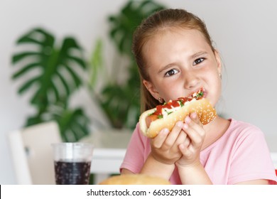 Young Cute European Girl In T-shirt Is Eating Unhealthy Food Like Hot Dog And Chips At Sunny Day