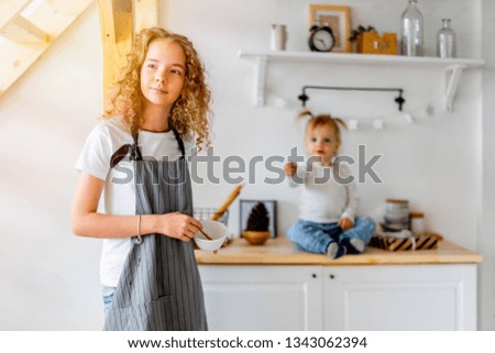 Young cute girl and her toddler sister preparing breakfast for parents.