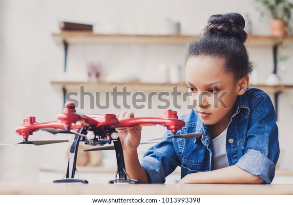Young cute girl holding quadcopter. Child\
playing with drone at home. Education, home studying, children,\
technology, science, future and people\
concept