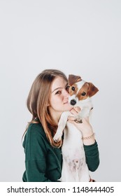 Young Cute Girl Holds And Hugs Her Puppy Jack Russell Terrier Dog.Girl Smiles And Looksat The Camera.Love Between Owner And Dog. Isolated On White Background. Studio Portrait.